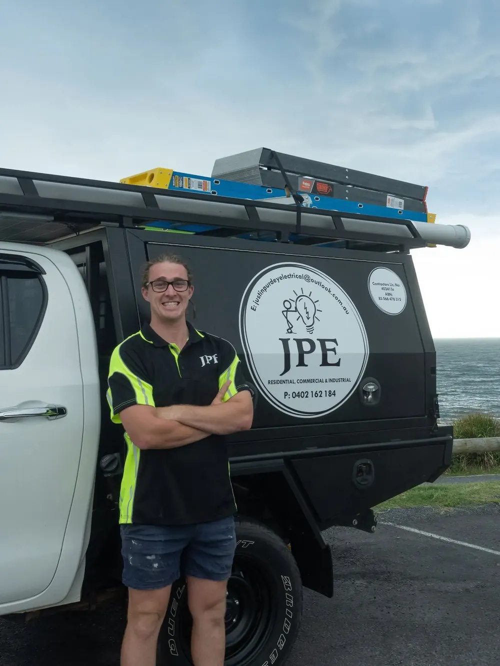 Justin Purdey standing beside the Justin Purdey Electrical ute on the coast