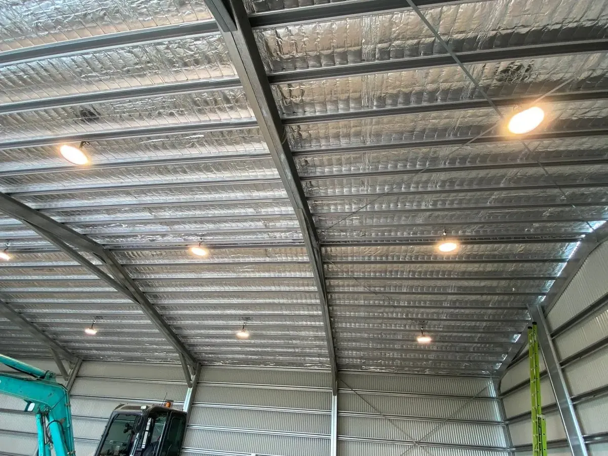 A large shed lit by LED high-bay fittings with an excavator parked inside