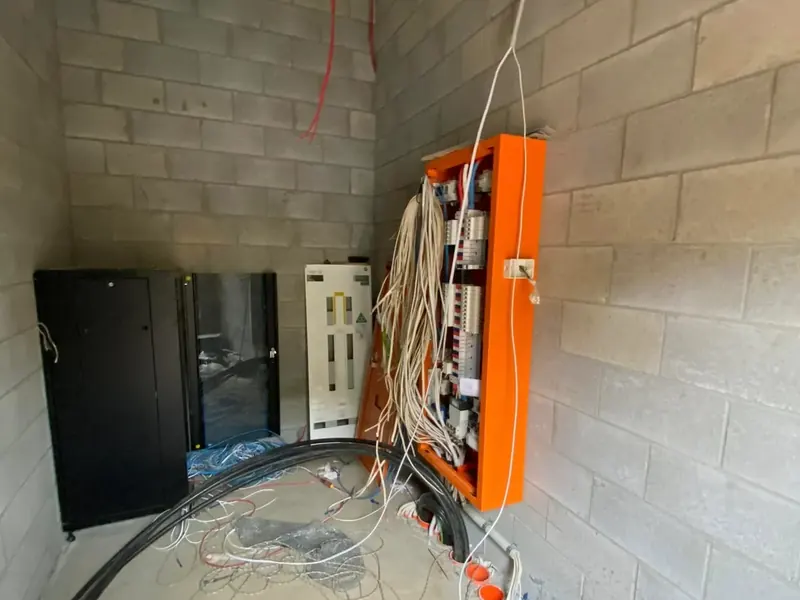 A sub-board and cabling mounted on the blockwork wall of an industrial building