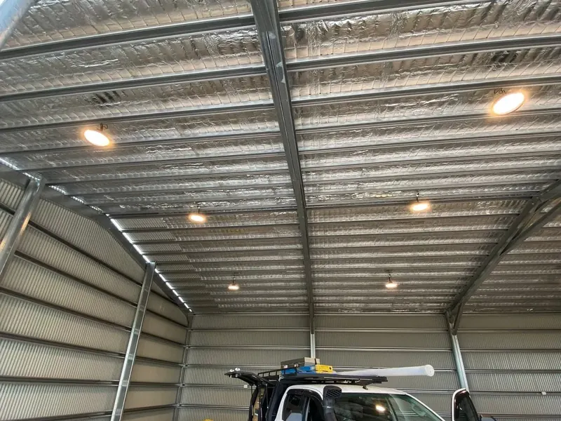 A shed interior lit by LED downlights with a work ute parked inside