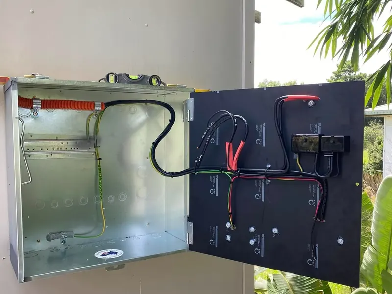 An outdoor meter enclosure opened up with its wiring and main switch visible